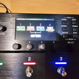 Černý kytarový procesor s nápisem FRACTAL AUDIO SYSTEMS a označením AM4 AMP MODELER. Zařízení má digitální displej, který zobrazuje menu s položkami…