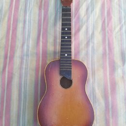 Akustická kytara s tělem v červenohnědém sunburst provedení. Hmatník je tmavý s bílými polohovými značkami, hlava kytary je bez ladíček a strun. Na h…