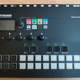 Černý sekvencer s nápisem PYRAMID polyrhythmic 64track sequencer a značkou Squarp instruments. Zařízení obsahuje displej, pět otočných ovladačů, něko…