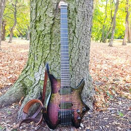 Elektrická kytara s tmavě fialovým průsvitným lakem a viditnou strukturou dřeva. Nástroj má dva humbuckery, ovládací knofíky a hrazdici most. Na hlav…