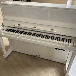 Bílý pianino s glossy povrchem a bílými nohami. Nad klávesnicí je v centru umístěn nápis SAMICK. Nástroj vykazuje čistý povrch bez viditelného opotře…