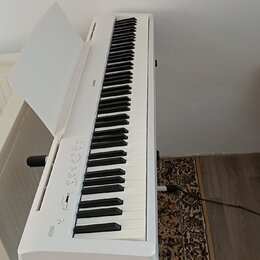 Bílé digitální piano na bílém stojanu s otevřeným krytem klávesnice. Na levé straně je nápis ES110 a na horní hraně těla nápis KAWAI. Nástroj vykazuj…