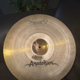 Kruhová mosazná činely s viditelným broušením povrchu. Na horní části je nápis Diamond a pod ním text 16"/40cm Trinity China s ikonou diamantu. Ve sp…
