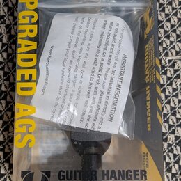 Fotografie znázorňuje držák na kytaru v původním balení. Na žlutém kartonu je nápis UPGRADED AGS, GUITAR HANGER a logo s textem HERCULES. Pod názvem…