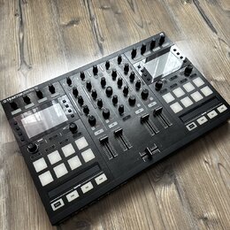 Černý DJ kontrolér s nápisem TRAKTOR KONTROL S5. Zařízení obsahuje několik faderů, zahlreichen otočných knoflíků a dvě sady bílých čtvercových podsví…