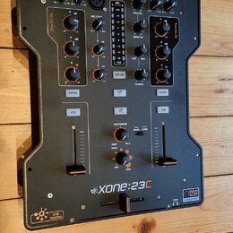 Černý DJ mixér značky ALLEN&HEATH, model Xone:23C. Na předním panelu jsou umístěny knofíky, posuvníky a tlačítka s nápisy jako MIX, MASTER, MONITOR,…