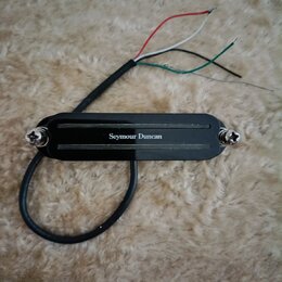 Černý humbucker s kovovými šrouby na okrajích. Uprostřed je bílý nápis Seymour Duncan. Z nástroje vede černý kabel zakončený čtyřmi barevnými vodiči…