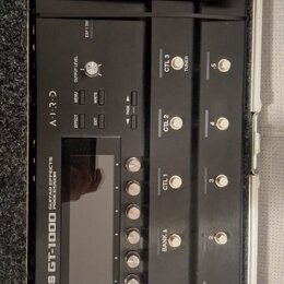 Černý kytarový procesor BOSS GT-1000 umístěný v transportním kufru. Na přístroji jsou viditelné nápisy GUITAR EFFECTS PROCESSOR, AIRD a ovládací prvk…