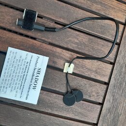 Černý kabel s dvěma kulatými lepicími senzory na koncích a suchým zipem v horní části. Vedle kabelu je bílý papírový návod s nápisem SHADOW Product I…