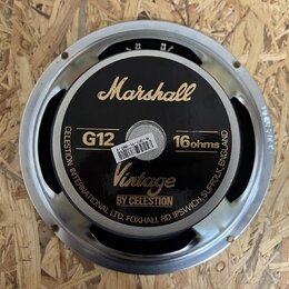 Fotografie znázorňuje zadní stranu reproduktoru s kovovým rámem. Na černém krytu jsou zlaté nápisy Marshall, Vintage BY CELESTION a bílé označení G12…