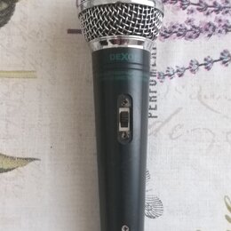 Černý dynamický mikrofon s kovovou stříbrnou mřížkou. Na horní části těla je bílý nápis DEXON a pod ním drobným písmem text ELECTRODYNAMIC MICROPHONE…