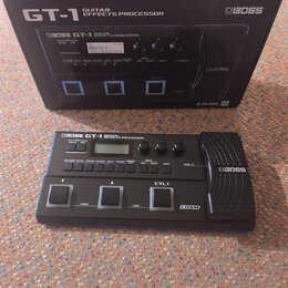 Černý kytarový procesor BOSS GT-1 v originální krabici. Na přístroji i na obalu jsou viditelné nápisy BOSS GT-1 GUITAR EFFECTS PROCESSOR a logo COSM.…