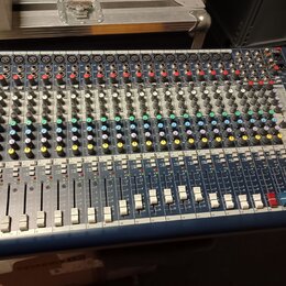 Modrý mixážní pult s kovovým panelem a множеstvem potenciometrů, přepínačů a posuvníků. V pravé dolní části je viditelné logo Soundcraft a označení m…