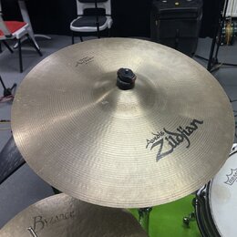 Fotografie zachycuje dva činely v mosazné barvě. Horní činel nese nápisy „Avid 6 Zildjian“ a v horní části menší text „THE GONG“. Spodní činel má náp…
