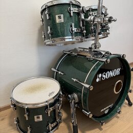 Sada bubnů v tmavě zelené barvě s chromovaným hardwarem. Na basovém bubnu je bílé logo SONOR a nápis DRUMCENTER.CZ, na ostatních bubnech jsou viditel…