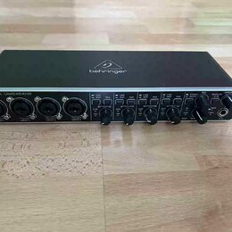 Černý audio rozhraní s nápisem behringer na horní straně a označením U-PHORIA UMC404HD v levém horním rohu. Přední panel obsahuje čtyři kombinované v…