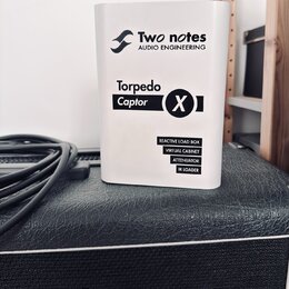 Bílý hranatý přístroj s nápisy Two notes AUDIO ENGINEERING a Torpedo Captor X. Dole jsou uvedeny funkce REACTIVE LOAD BOX, VIRTUAL CABINET, ATTENUATO…