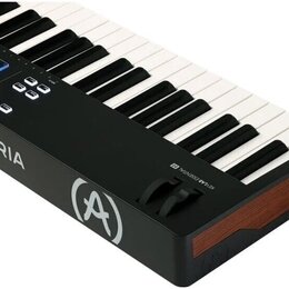 Černý MIDI kontrolér s klávesnicí a modrými podsvícenými pady. Na boku je bílý nápis ARTURIA a logo ve tvaru stylizedovaného písmene A v kruhu. V pra…