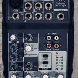 Tmavě šedý mixážní pult s bílými a červenými popisky. Na horní části je nápis XENYX 502, pod ním text PREMIUM 5-INPUT 2-BUS MIXER • XENYX MIC PREAMP…