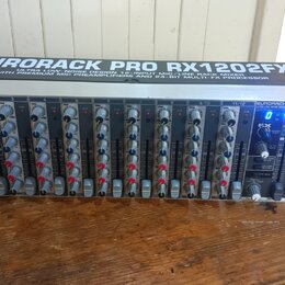 Stříbrný rackový mixážní pult s černým předním panelem. Na horní části je nápis EURORACK PRO RX1202FX a pod ním text ULTRA LOW-NOISE DESIGN 12-INP. M…