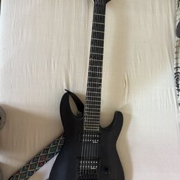 Černá elektrická kytara s matným povrchem a šesti strunami. Na hlavě hmatníku je bílý nápis Jackson. Nástroj má dva humbuckery, jeden ovládací knoflí…