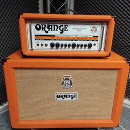 Kytarový zesilovač s oranžovým potahem, složený z hlavy a reproduktorové skříně. Na hlavě je nápis ORANGE a model ROCKERVERB 50 MK II, s řadou ovláda…