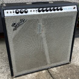 Kytarový kombozesilovač s černým krytím z vinylu a stříbrnou tkanou přední síťovkou. Na horním ovládacím panelu jsou nápisy NORMAL, VIBRATO a SUPER R…