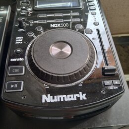 Černý DJ kontroler značky Numark s modelem NDX500. Zařízení obsahuje velký stříbrno-černý jogwheel, posuvník pitch bend a řadu tlačítek s nápisy jako…