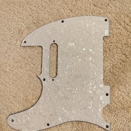 Bílá pickguard s perleťovým vzorem pro elektrickou kytaru. Je vyrobena z plastového materiálu a obsahuje výřezy pro snímače a ovládací prvky. Povrch…