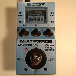 Modrý efekt pedál značky ZOOM s nápisem MULTISTOMP MS-70CDR Chorus Delay Reverb. Na horní straně je LCD displej zobrazující schéma efektů a tři černé…