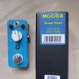 Modrý efekt pedál s bílým ovládacím knoflíkem, dvěma černými potenciometry a přepínačem. Na pedálu jsou nápisy „Blues Mood“ a „MOOER“. Vedle je černá…
