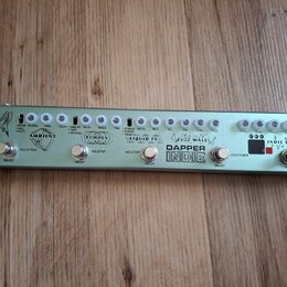 Stříbrný efektový pedalboard s nápisem DAPPER INDIE. Obsahuje pět sekcí s ovládacími knoflíky a přepínači, které jsou označeny názvy AMBIENT, ECHOES,…