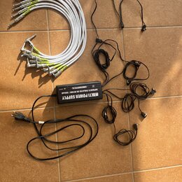Na fotografii je černý napájecí adaptér s nápisem MULTI POWER SUPPLY, SEPARATE ISOLATED 8X DC10V / 100mA a značkou SMBCKALLIEFFECTS. K adaptéru patří…