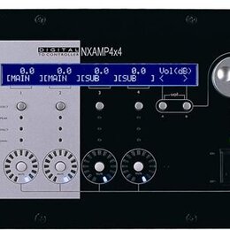 Černý rackový zesilovač s bílo-stříbrným předním panelem v levé části. Na panelu je modrý LCD displej s hodnotami 0.0 pro kanály CMAIN, JMAIN, JSUB a…