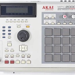 Světle šedý MIDI sampler MPC s 16 gumovými pady v mřížce 4x4. Na horní straně je nápis AKAI professional a model MPC2000XL MIDI PRODUCTION CENTER. Za…