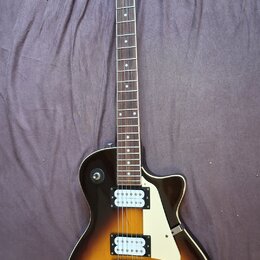 Elektrická kytara s trupem v tmavě hnědé a žluté barvě (sunburst) a bílým pickguardem. Na hlavě hmatníku je nápis Samick a pod ním logo ve tvaru štít…
