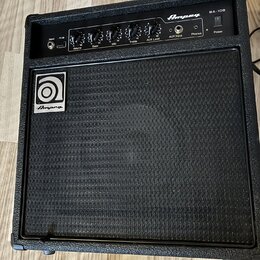 Černý basový kombozesilovač s texturovaným povrchem a černou přední síťovkou. Na horním ovládacím panelu je nápis Ampeg BA-108 a ovládací prvky s pop…