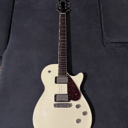 Bílá elektrická kytara s tvarem připomínajícím Les Paul a tmavým hmatníkem. Na hlavě je nápis KRAETEN. Nástroj má dva humbuckery, tmavě červený plech…