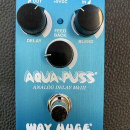 Modrý kytarový efekt s nápisy AQUA-PUSS, ANALOG DELAY MkIII a WAY HUGE. Na horní straně jsou tři černé otočné knoflíky s popisky DELAY, FEED BACK a B…