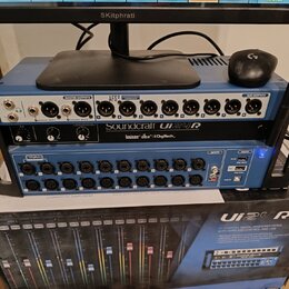 Modrý digitální mixážní pult s nápisy Soundcraft Ui24R a logy lexicon, dbx a DigiTech. Zařízení má řadu vstupních a výstupních konektorů XLR a jack,…