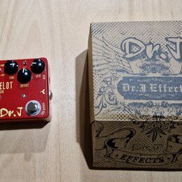 Červený kytarový efekt s nápisy LANCELOT DISTORTION a Dr. J. Na horní straně jsou tři černé otočné knoflíky s popisy DIST BOOST, TONE a GAIN. Na spod…
