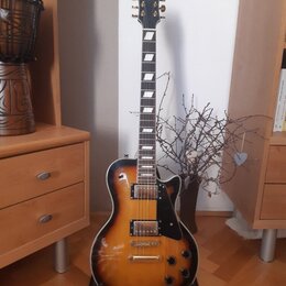 Elektrická kytara s tvarem singlecut a barevným přechodem od žluté k tmavě hnědé (sunburst). Na hlavě je viditelné logo Epiphone. Nástroj má dva humb…