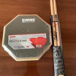 Na fotografii je v originálním balení cvičný pad značky EVANS s nápisem REALFEEL a MOUNTABLE PRACTICE PAD. Pad má šestiúhelníkový tvar, šedý povrch a…