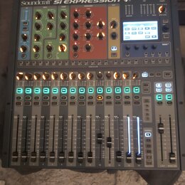 Digitální mixážní pult šedé barvy s nápisem Soundcraft SI EXPRESSION. Horní část obsahuje barevně rozdělené sekce s ovládacími knoflíky v modré, zele…