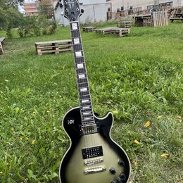Elektrická kytara s tmelem v černé barvě s přechodem do stříbrno-šedé (sunburst). Na hlavě je viditelné logo Epiphone. Kytara má dva humbuckery, čtyř…