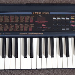 Elektronický klavír v tmavě šedém plastovém provedení. Na horním panelu je nápis KAWAI FS780 a v dolní části panelu text PROGRAMMABLE ONE FINGER AD-L…