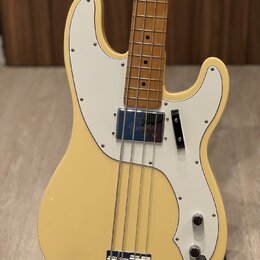 Krémově bílá elektrická basová kytara s bílým pickguardem a hnedým hmatníkem ze dřeva. Na chromovaném krytu snímače je viditelné logo "Gretsch". Nást…