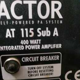 Detailní záběr na zadní panel černého aktivního subwooferu. Je zde uveden nápis ACTOR, ELF-POWERED PA SYSTEM a model AT 115 Sub A. Dále je vidět text…