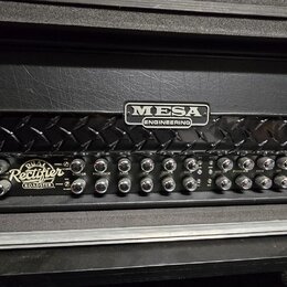 Kytarový zesilovač s černým povrchem a chromovanými detaily. Na předním panelu je logo MESA ENGINEERING a nápis Dual Rectifier ROADSTER. Přístroj obs…