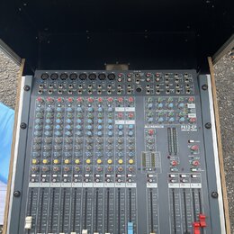 Šedý mixážní pult umístěný v transportním kufru. Na přístroji je vidět bílý nápis ALLEN&HEATH a označení modelu PA12-CP CONSTANT POWER. Povrch pultu…